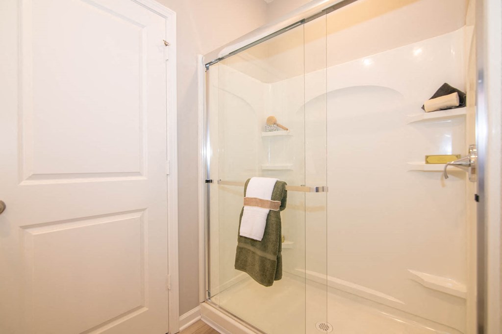 a bathroom with white tiles and a glass door at Jackson Run Townhomes, Whitestown Indiana