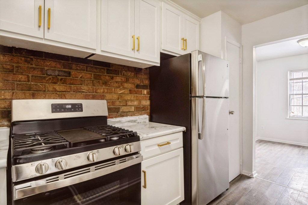 a kitchen with white cabinets and a brick wall