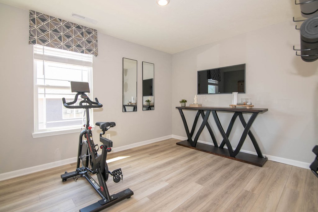 a home gym with a exercise bike in front of a window at Jackson Run Townhomes, Whitestown