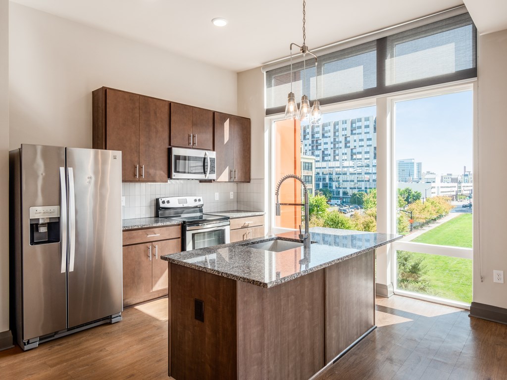 A modern kitchen with a refrigerator, microwave, oven, and sink.