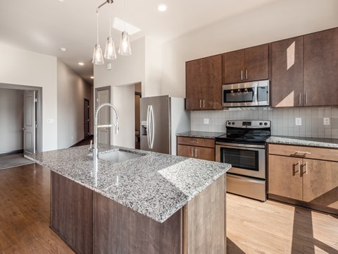 A kitchen with a granite countertop and wooden cabinets.