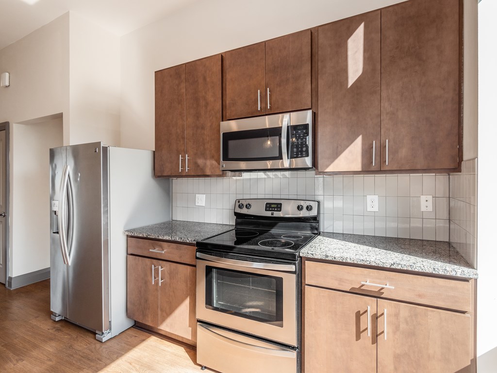 A kitchen with a stove, refrigerator, and microwave.