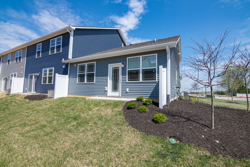 the front of a blue house with a lawn and shrubs at Jackson Run Townhomes, Whitestown, 46075