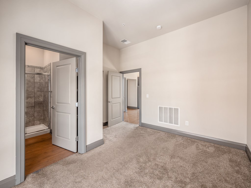 A room with a carpeted floor and a doorway leading to a bathroom.