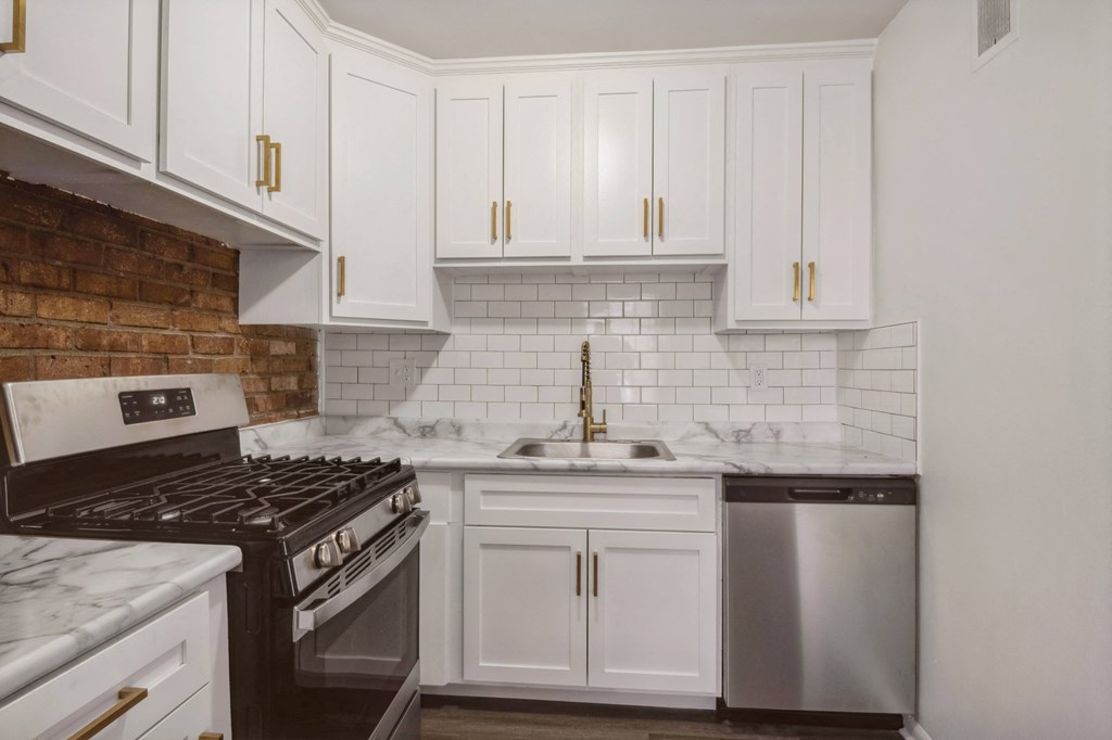 a kitchen with white cabinets and a brick wall