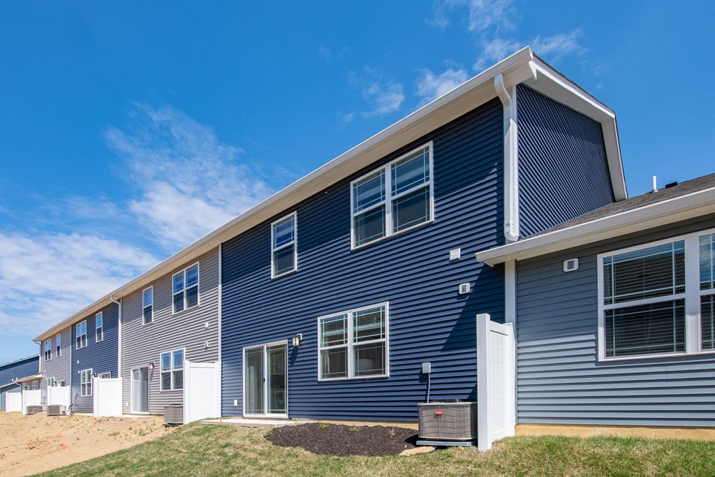 a blue house with white windows on a sunny day at Jackson Run Townhomes, Whitestown Indiana