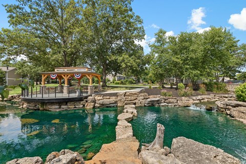 A gazebo sits on a rocky outcrop over a body of water.
