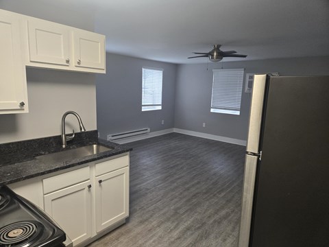 A kitchen with a black countertop and white cabinets.