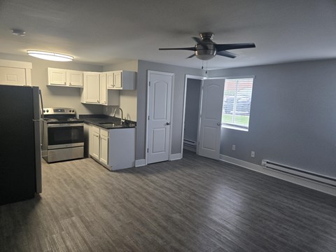 A kitchen with a black refrigerator and a fan on the ceiling.