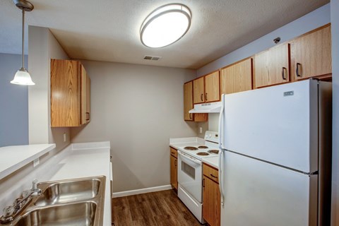 A kitchen with white appliances and wooden cabinets.