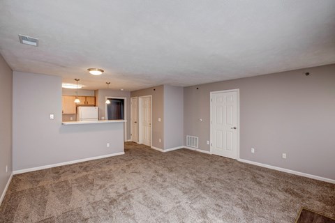 A spacious room with a carpeted floor and a ceiling fan.