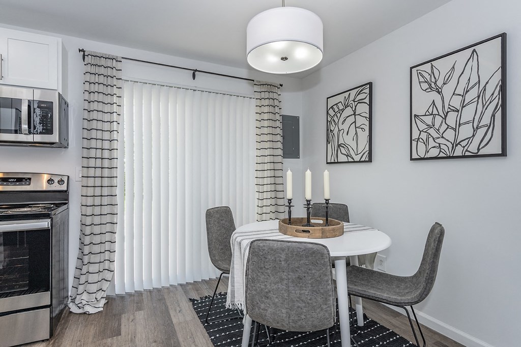 a dining room with a table and chairs and a window with blinds