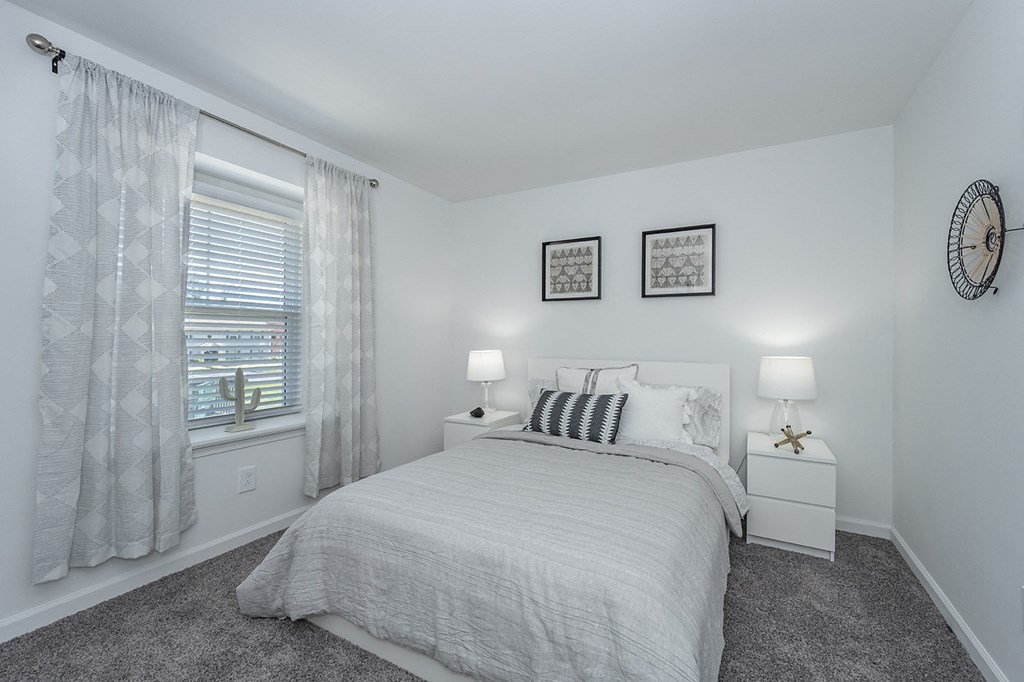 a white bedroom with a bed and a window