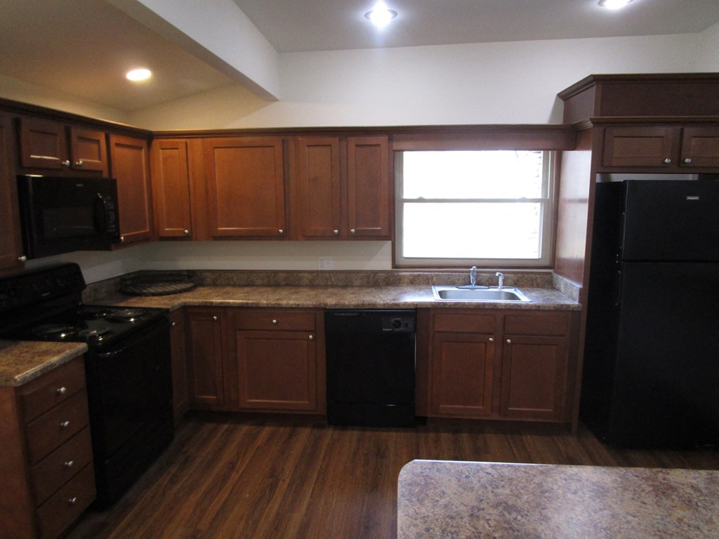 an empty kitchen with wooden cabinets and black appliances