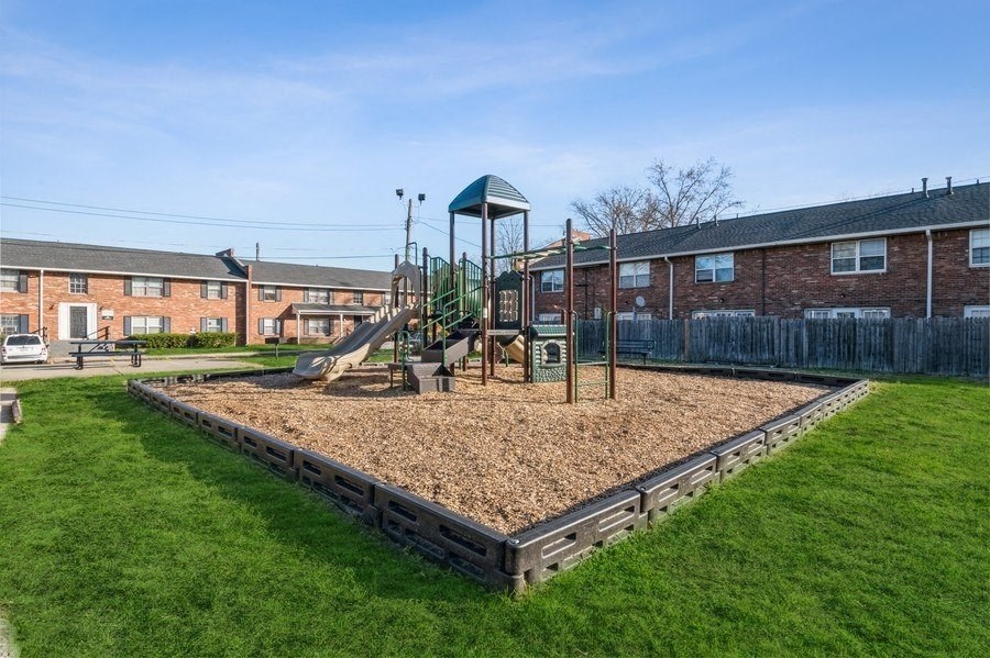 a playground with a swing set in the middle of a grassy area