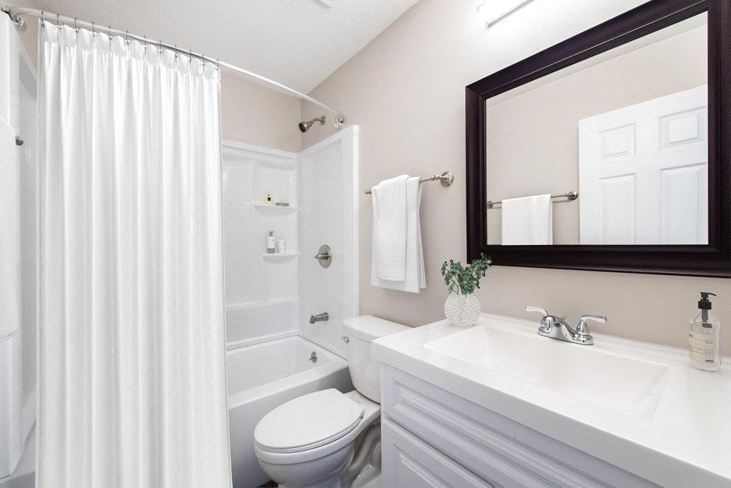 a bathroom with a white shower curtain and a white toilet next to a white sink with a