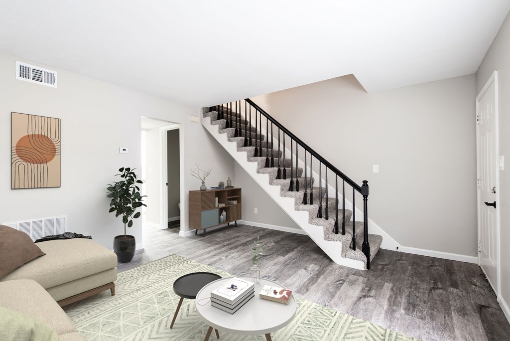 a living room with a staircase in the background and a couch and coffee table in the foreground