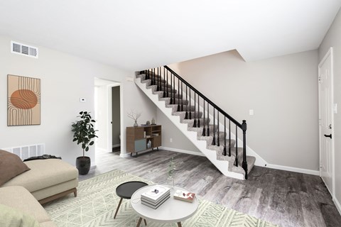 a living room with a staircase and a couch and a coffee table