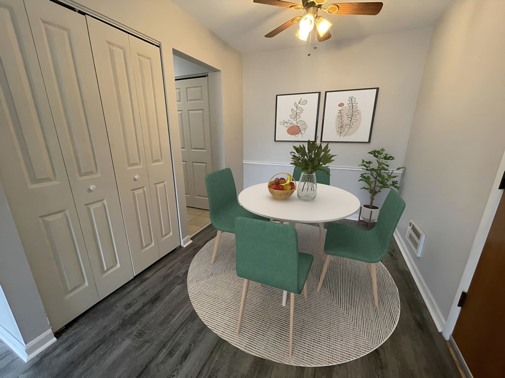 a dining area with a round table and four green chairs