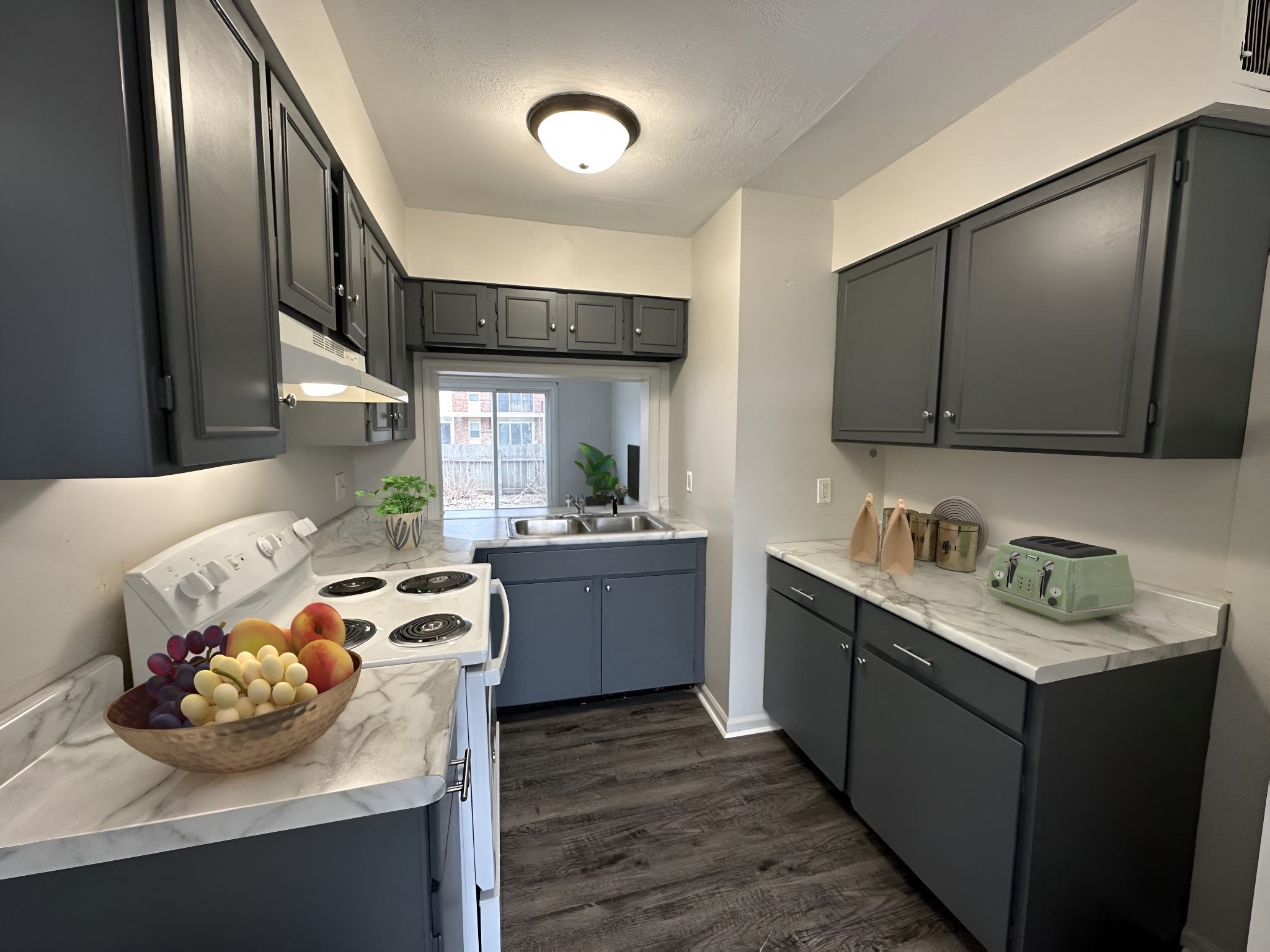 a kitchen with gray cabinets and a bowl of fruit on the counter