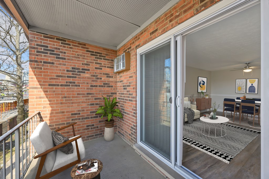 a balcony with a sliding glass door and a bed in a room with a dining table and