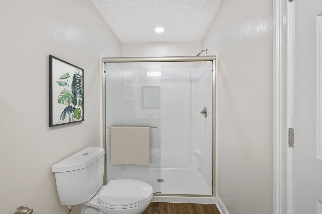 a bathroom with a toilet and a shower with a glass door at Harpers Point Apartments, Cincinnati, OH