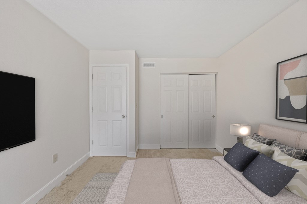 a bedroom with two doors and a tv on the wall at Harpers Point Apartments, Cincinnati, OH