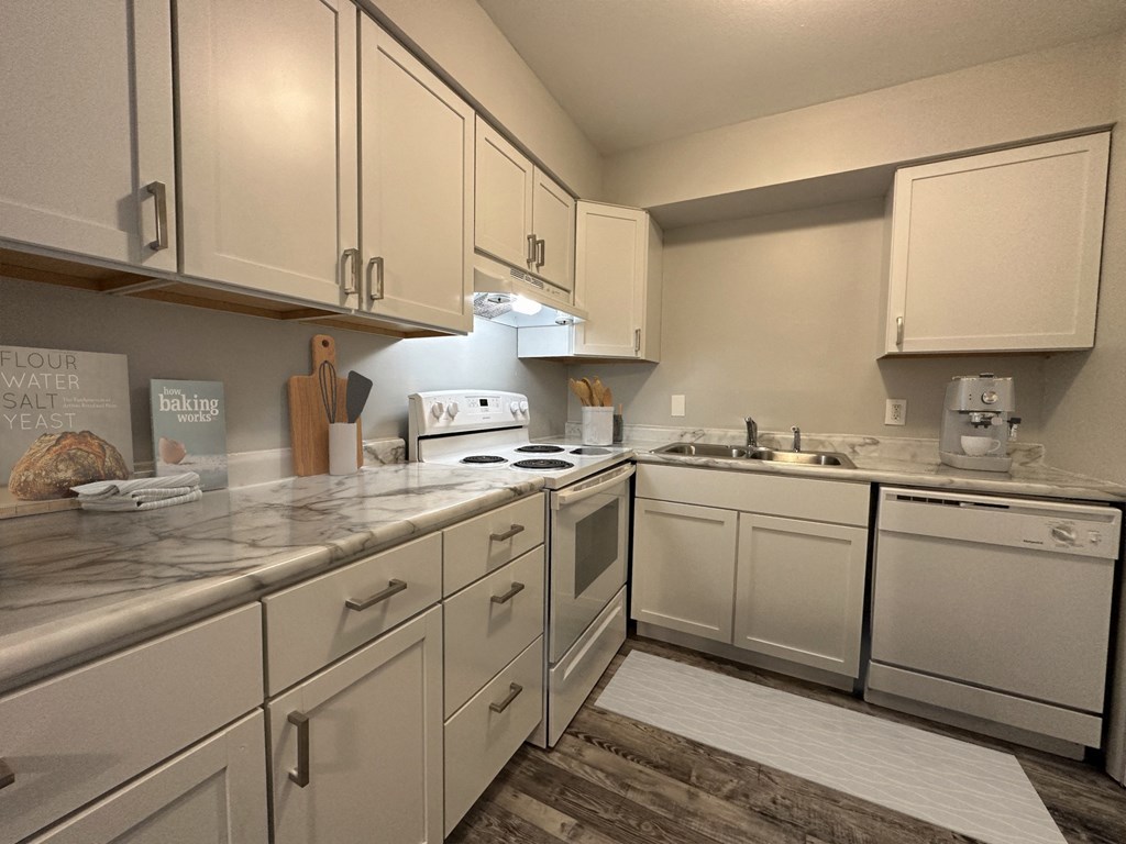 a kitchen with white cabinets and a white rug