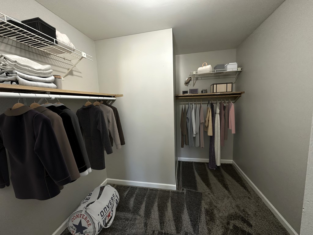 a walk in closet with a mirror and a rack of clothes