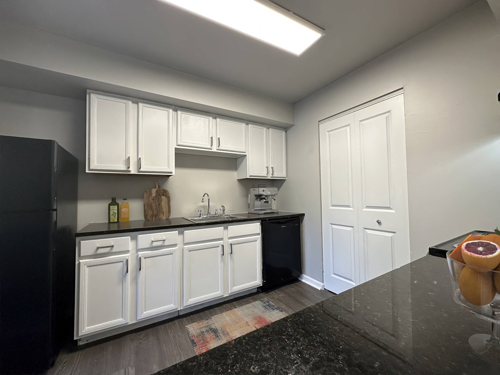a kitchen with white cabinets and a black counter top