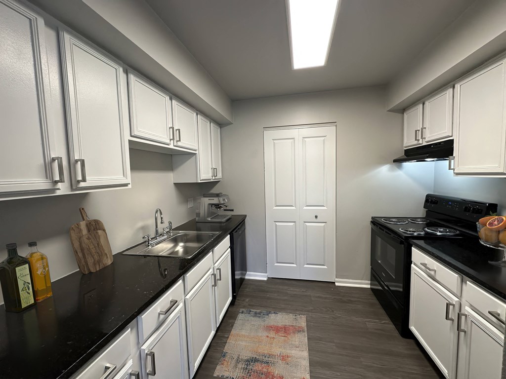 a kitchen with white cabinets and black counter tops