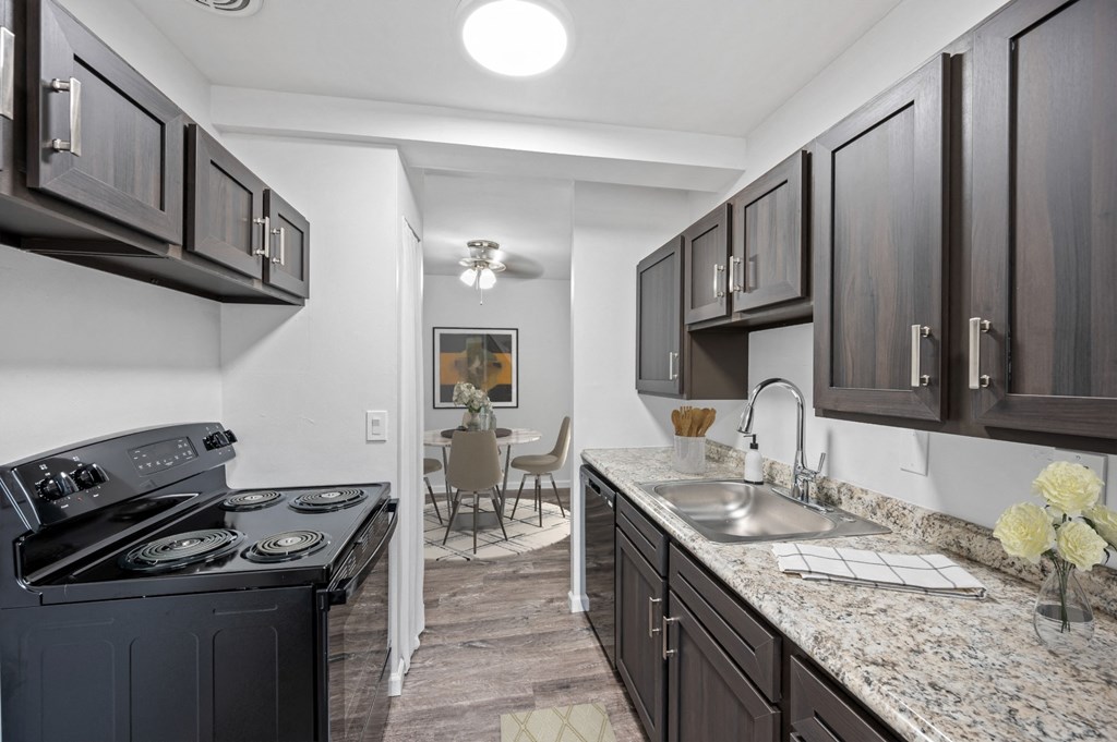 a kitchen with dark wood cabinets and granite counter tops and a black stove and sink