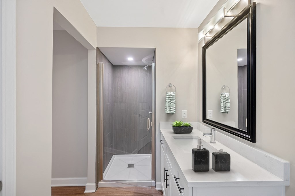 a white bathroom with a large mirror and a shower at Indian Creek Apartments, Cincinnati, OH