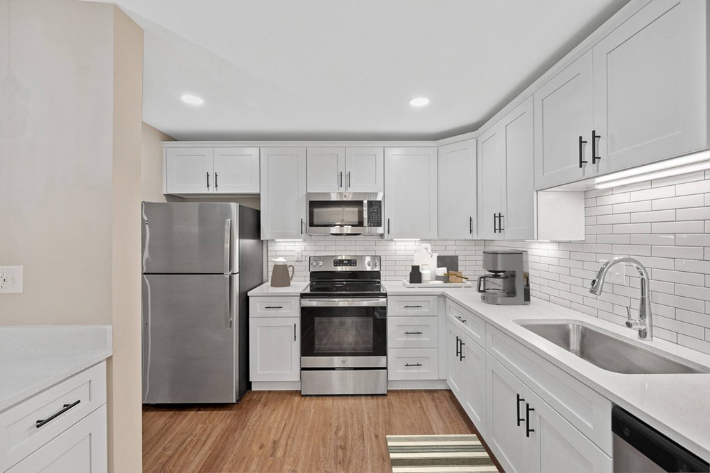 a white kitchen with stainless steel appliances and white cabinets at Indian Creek Apartments*, Cincinnati, OH