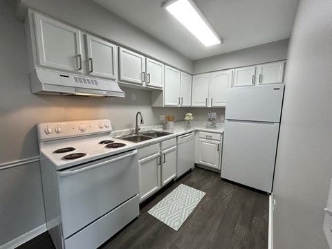 A white kitchen with a stove, sink, and refrigerator.