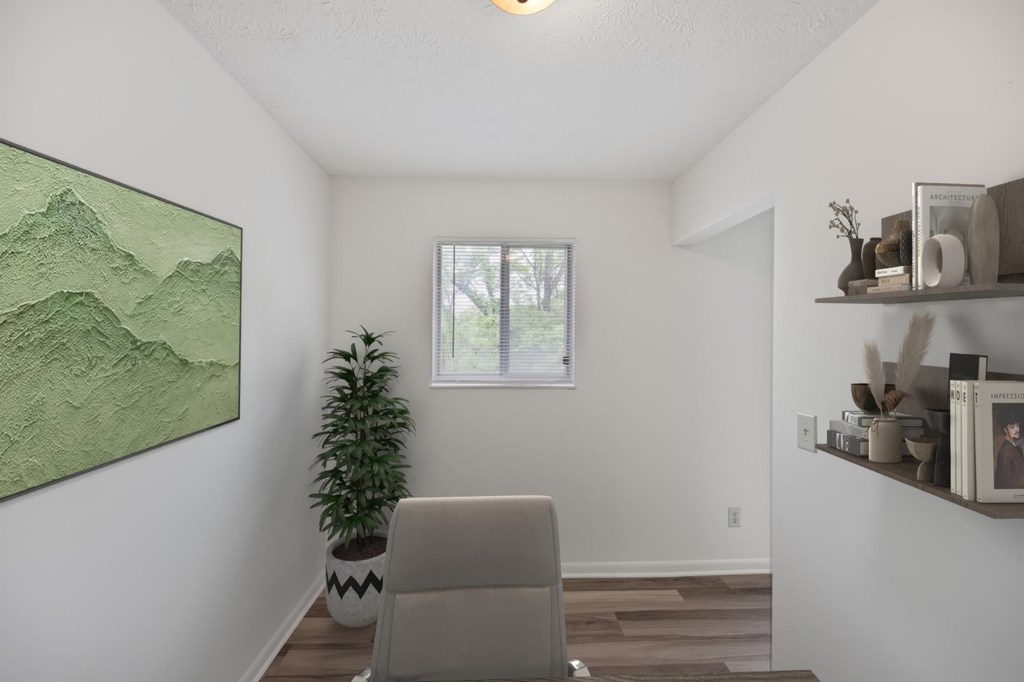 A room with a painting, a plant, and a chair.