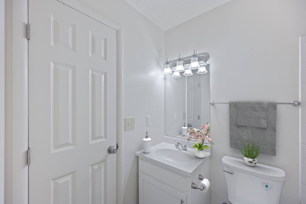 A white bathroom with a toilet, sink, and mirror.