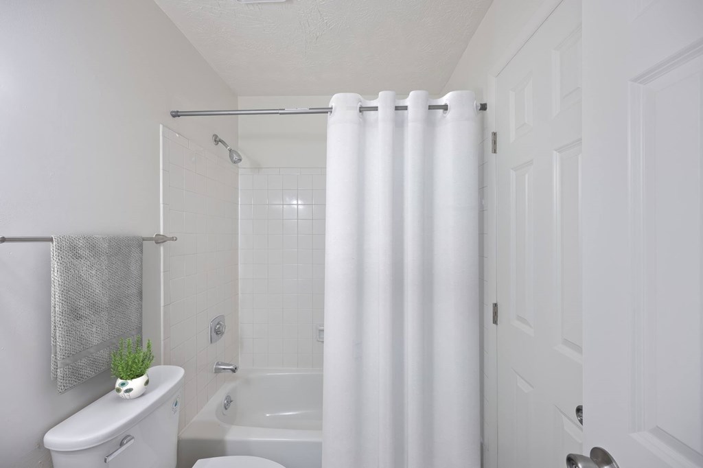 A white bathroom with a toilet, sink, and shower.
