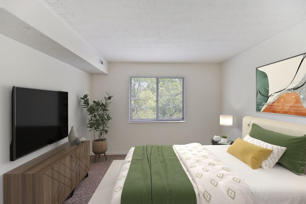 A bedroom with a bed, a television, and a plant.