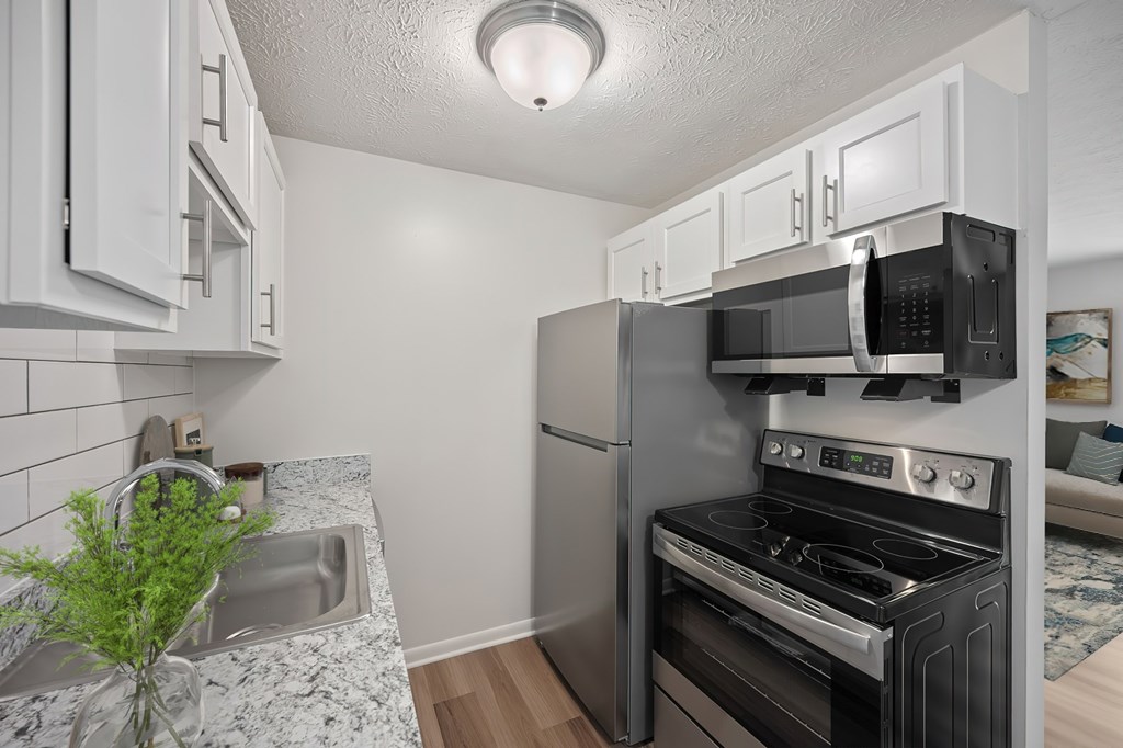 A kitchen with a sink, stove, and microwave.