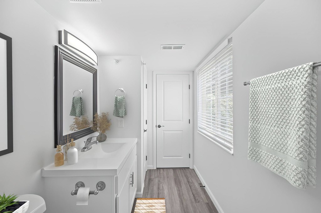 A white bathroom with a mirror, sink, and shower curtain.