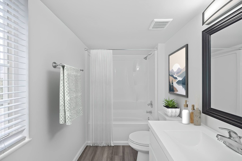 A white bathroom with a toilet, sink, and shower.