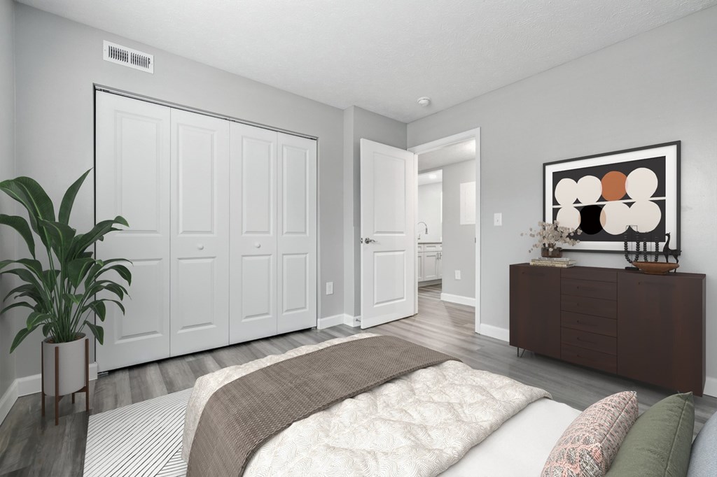 A bedroom with a bed, a plant, and a painting on the wall.