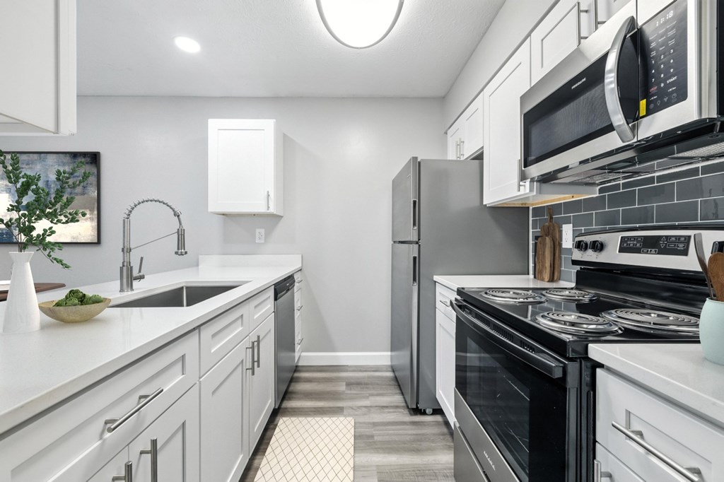 A modern kitchen with white cabinets and stainless steel appliances.
