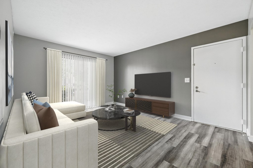 A living room with a white couch, a coffee table, and a flat screen TV.