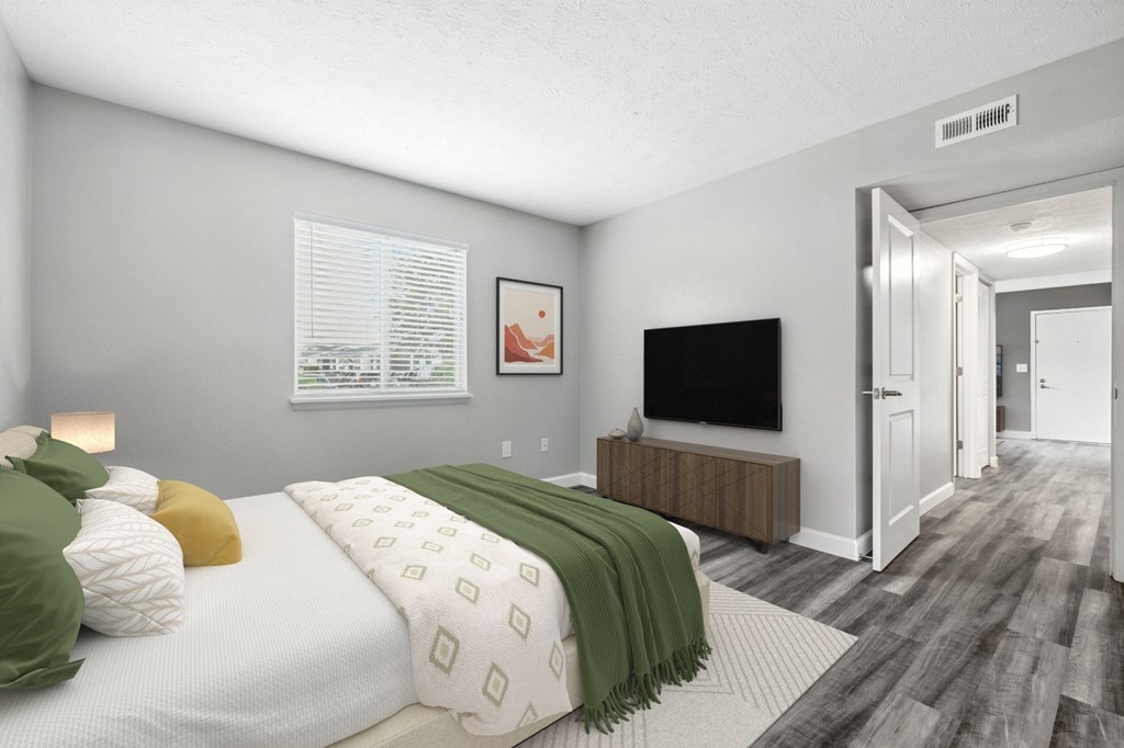 A bedroom with a bed, a television, and a mirror.