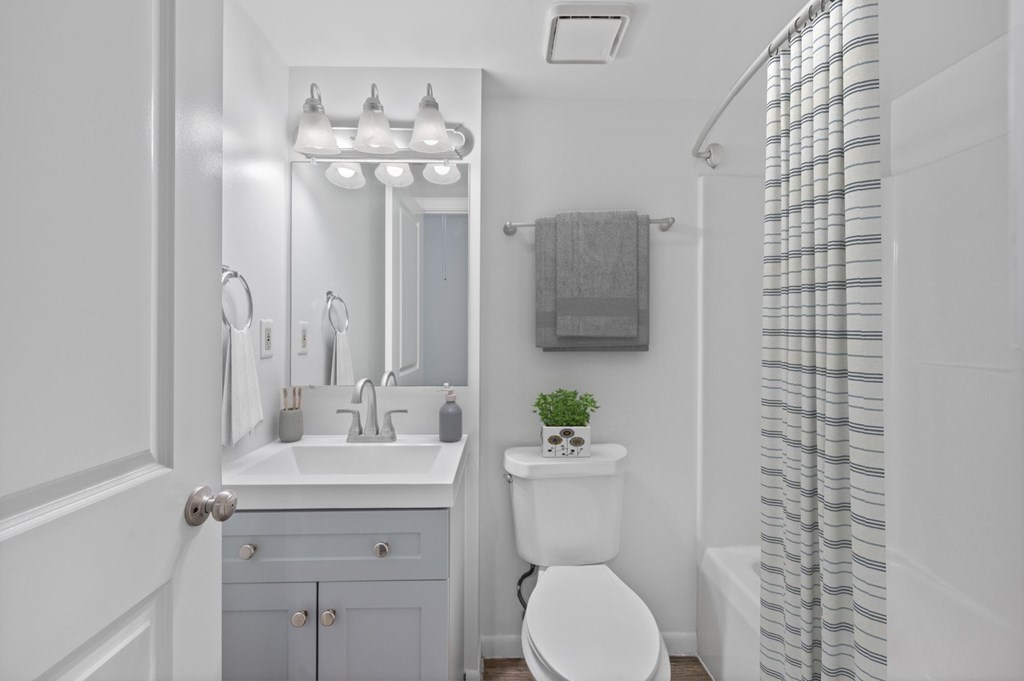 A white bathroom with a toilet, sink, and mirror.