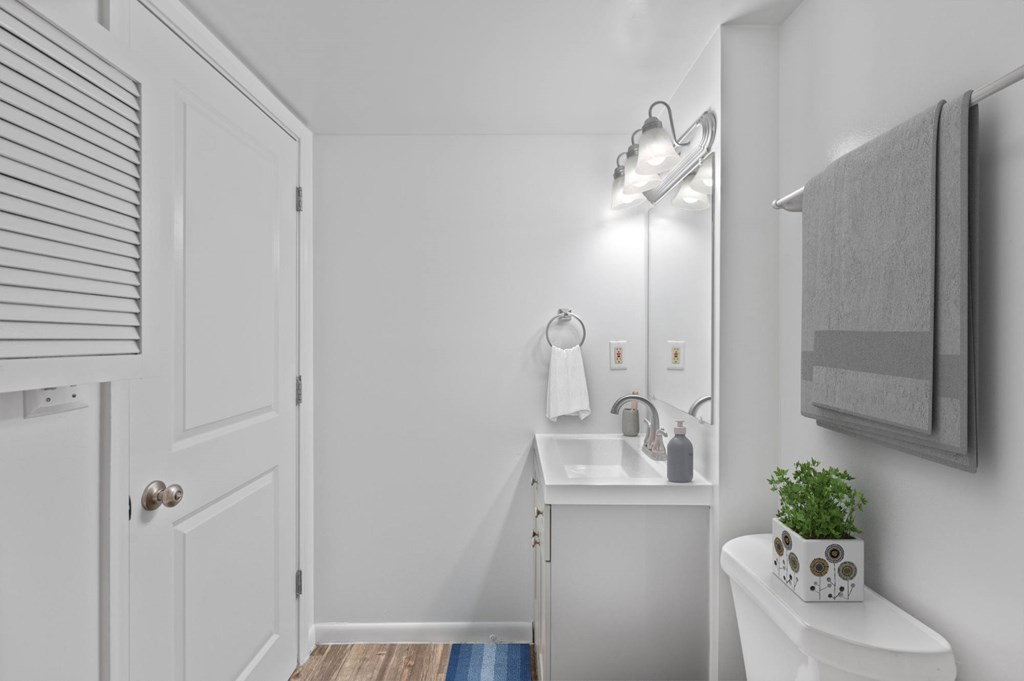 A small white bathroom with a toilet, sink, and a light fixture.