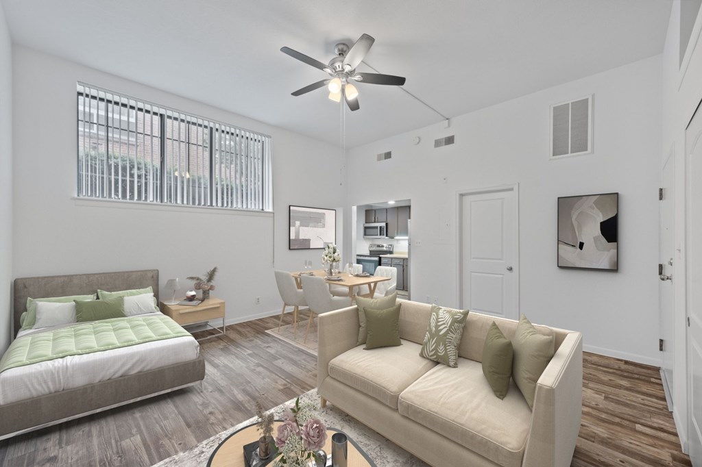 A living room with a couch, a bed, and a ceiling fan.