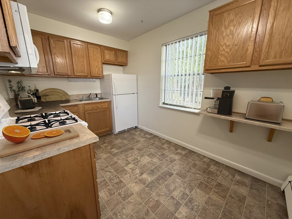 A kitchen with a white refrigerator and wooden cabinets.